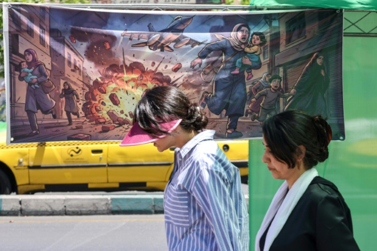 Une Iranienne passe devant une banderole représentant l'attaque américano-israélienne contre l'Iran, dans la capitale Téhéran, le 9 mai 2026 ( AFP / ATTA KENARE )