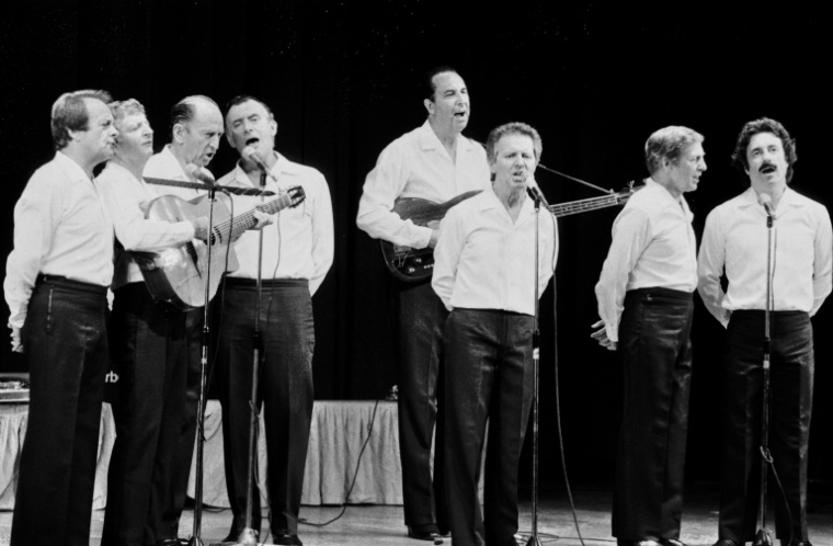 Les Compagnons de la chanson, à l'Olympia, leur scène fétiche, à Paris le 24 aout 1983. Michel Cassez, surnommé Gaston (Premier en partant de la droite), dernier des Compagnons, est décédé le 25 mai 2025 à l'âge de 93 ans, à Vaison-la-Romaine (Vaucluse). ( AFP / JACQUES POSTEL )