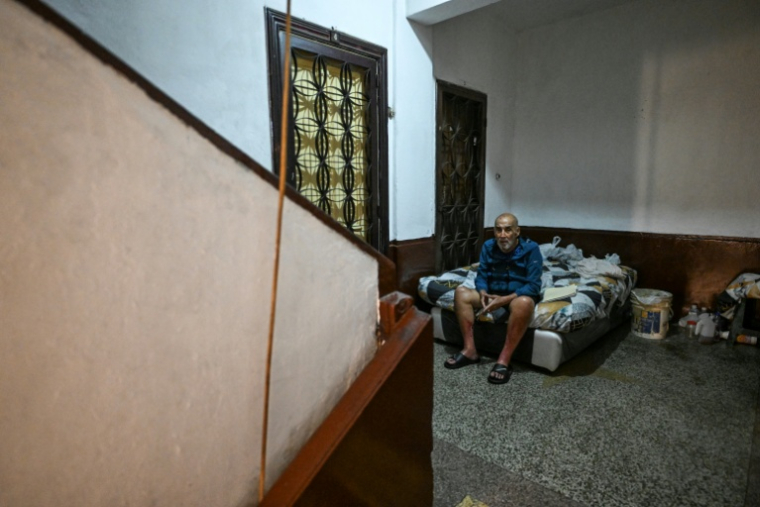 José Breijo assis sur un lit dans le couloir d'un immeuble résidentiel à Caracas, le 26 mai 2026 au Venezuela ( AFP / Juan BARRETO )