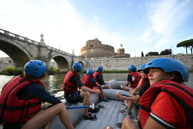 Des personnes naviguent en canot pneumatique sur le Tibre, passant devant le château Saint-Ange, sur un tronçon du fleuve situé entièrement dans la zone urbaine du centre de Rome, le 14 août 2026 ( AFP / Andreas SOLARO )