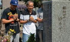 Jose Villafuerte (au centre) prie avec son fils sur la tombe de son père à Takatsuki, au Japon, le 7 août 2025 ( AFP / Fred MERY )