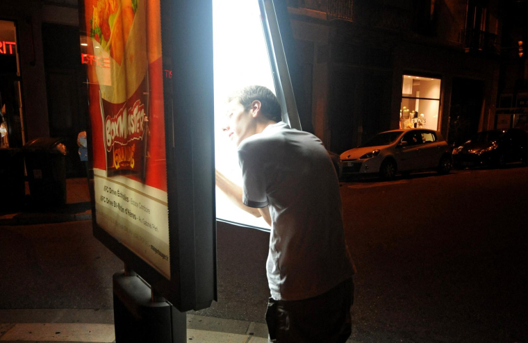 Un membre du Clan du Néon éteint le néon d’une publicité pour économiser l’électricité à Grenoble, le 9 juillet 2012 (Illustration). ( AFP / JEAN-PIERRE CLATOT )