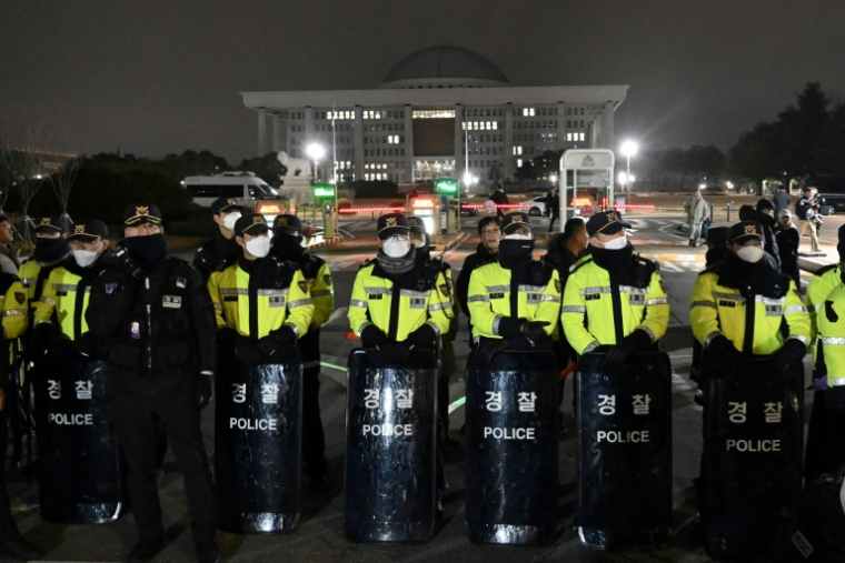 Des policiers montent la garde devant l'entrée principale de l'Assemblée nationale à Séoul, tard dans la soirée du 3 décembre 2024, après que le président sud-coréen Yoon Suk Yeol a déclaré la loi martiale ( AFP / Jung Yeon-je )