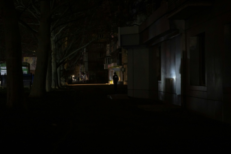Une rue plongée dans l'obscurité lors d'une panne de courant à Odessa, dans le sud de l'Ukraine, après des attaques de missiles et de drones russes contre les infrastructures énergétiques ukrainiennes, le 22 décembre 2025  ( AFP / Oleksandr GIMANOV )