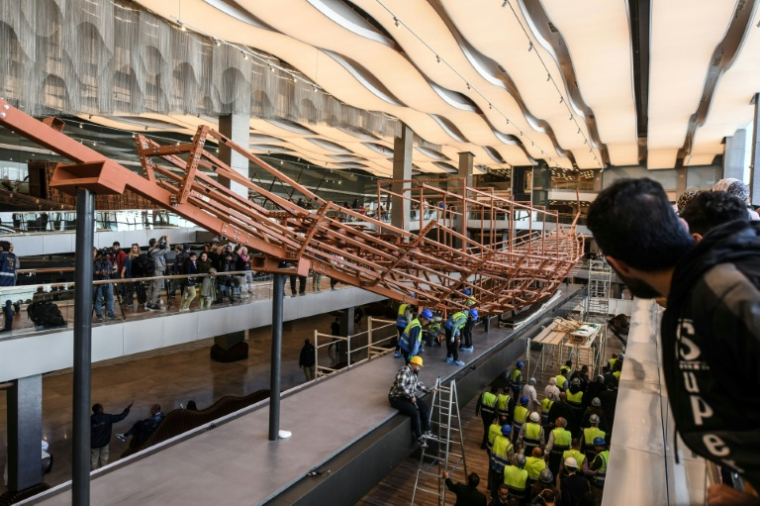 Des employés installent des planches de bois anciennes provenant de la deuxième barque du roi Khéops sur une structure métallique au Grand Musée égyptien de Gizeh, en périphérie du Caire, le 23 décembre 2025 ( AFP / Ahmed HASAN )