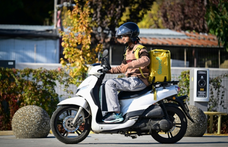 Un livreur de repas étranger circule en scooter dans une rue de Bucarest, le 10 octobre 2025 en Roumanie ( AFP / Daniel MIHAILESCU )