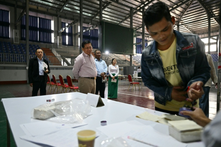 Le chef de la junte birmane Min Aung Hlaing (centre) observe le vote dans un bureau de Mandalay lors des législatives du 25 janvier 2026  ( AFP / ANTHONY WALLACE )