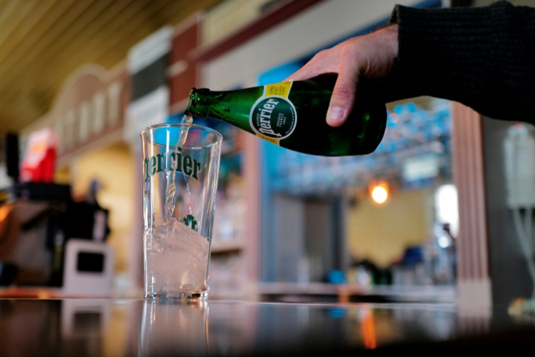 Un homme sert de l'eau minérale pétillante Perrier dans un verre à Vergèze, le 7 février 2025 dans le Gard ( AFP / Sylvain THOMAS )