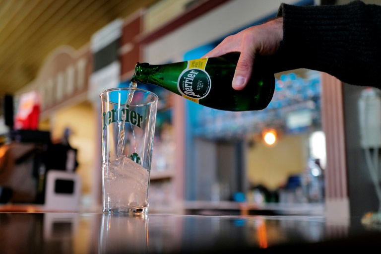 Un homme sert de l'eau minérale pétillante Perrier dans un verre à Vergèze, le 7 février 2025 dans le Gard ( AFP / Sylvain THOMAS )