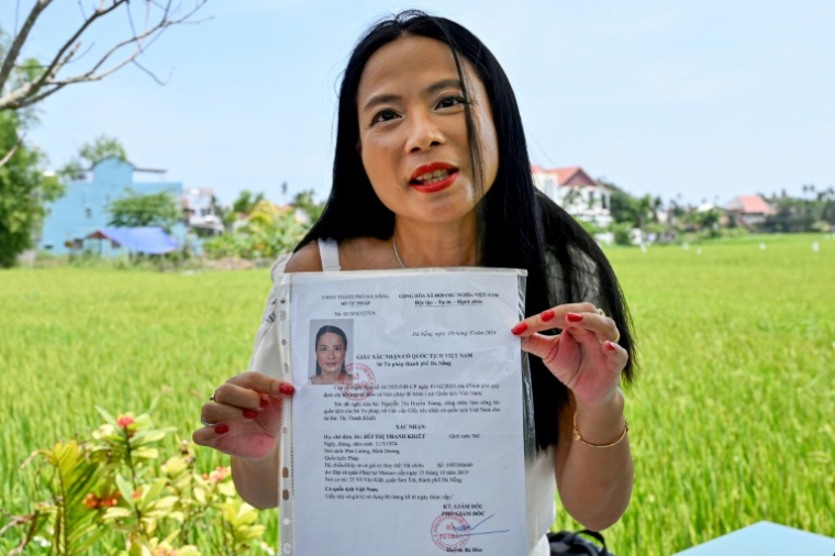Odile Dussart, évacuée de Saïgon alors qu'elle n'était qu'un bébé de 11 mois, quelques semaines avant la fin de la guerre du Vietnam il y a 50 ans, montre son certificat de nationalité vietnamienne dans sa nouvelle maison à Hoi An, le 12 avril 2025 ( AFP / Nhac NGUYEN )