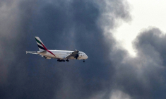 Un Airbus A380 d'Emirates se prépare à atterrir à l'aéroport de Dubaï d'où s'élève une épaisse fumée noire d'un incendie, le 16 mars 2026 aux Emiras arabes unis ( AFP / - )