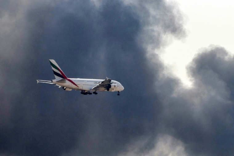 Un Airbus A380 d'Emirates se prépare à atterrir à l'aéroport de Dubaï d'où s'élève une épaisse fumée noire d'un incendie, le 16 mars 2026 aux Emiras arabes unis ( AFP / - )