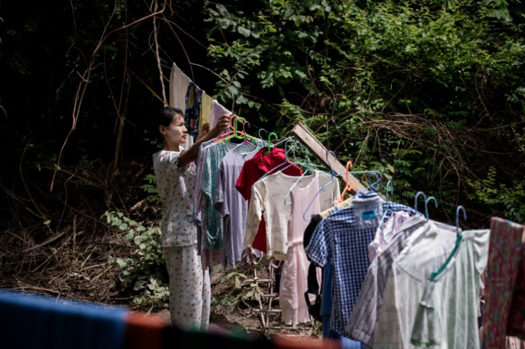 Une femme, déplacée par les combats entre l'armée birmane et l'Armée de l'indépendance kachin (KIA), étend du linge sur le terrain d'un monastère à Mandalay, le 16 septembre 2025 en Birmanie ( AFP / Sai Aung MAIN )