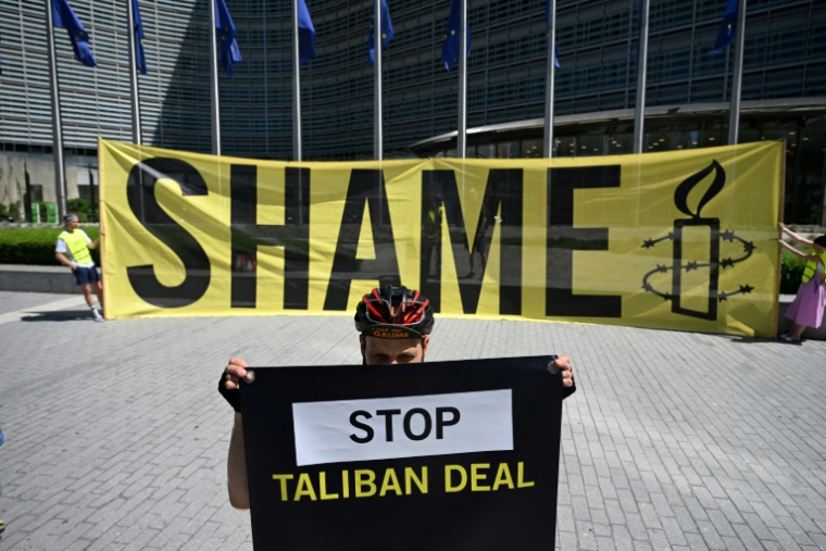 AUn militant d'Amnesty International tient une banderole "Stop Taliban deal" devant le siège de la Commission européenne pour protester contre une rencontre entre responsables talibans et européens à Bruxelles, le 23 juin 2026 ( AFP / Nicolas TUCAT )