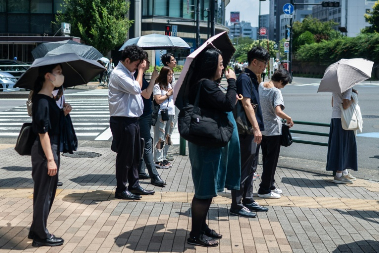 Les gens portent des parapluies pour se protéger du soleil à Tokyo le 23 juillet 2026 ( AFP / Andrew CABALLERO-REYNOLDS )
