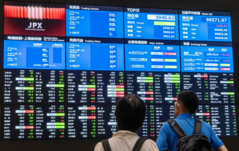 Des visiteurs devant les cours des valeurs à la Bourse de Tokyo le 1er juin 2026 ( AFP / Kazuhiro NOGI )