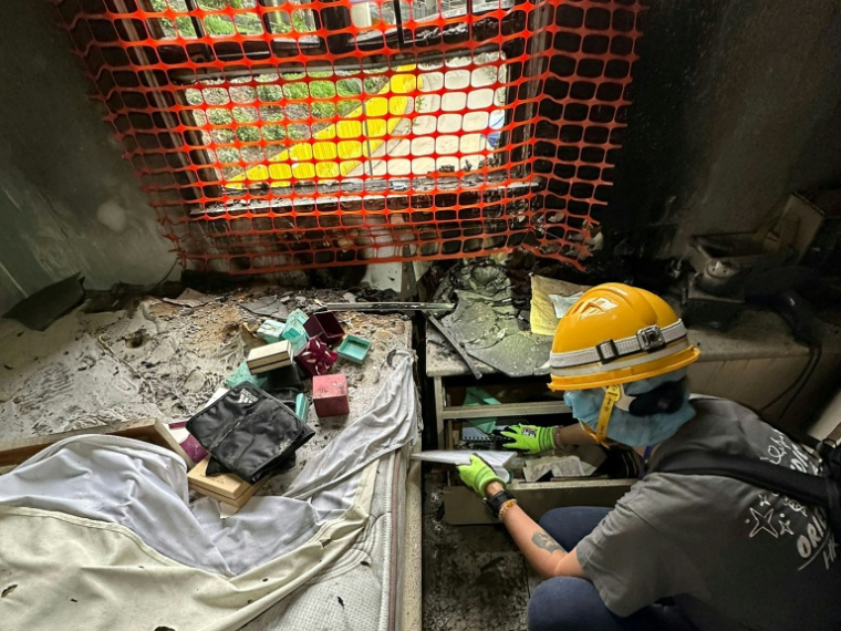 Sur cette photo prise et transmise le 23 avril 2026 par Bowie Chan, un habitant de Wang Fuk Court, son épouse Annie Tse fouille les tiroirs d'un meuble de leur appartement endommagé par l'incendie de novembre, à Hong Kong ( Courtesy of Bowie Chan / Bowie Chan )