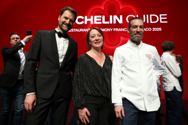 Michael Arnoult (D), chef du restaurant La Morainières, avec sa femme Ingrid et le directeur international des Guides Michelin, Gwendal Poullennec (G), après avoir reçu sa troisième étoile lors de la cérémonie de remise des prix du Guide Michelin 2026 à Monaco, le 16 mars 2026 ( AFP / Valery HACHE )