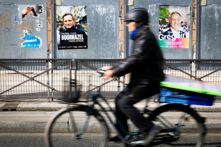 Un cycliste passe devant un panneau électoral avec les candidats à la mairie de Paris, le 7 mars 2026, à Paris ( AFP / JOEL SAGET )