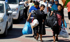 Photo des familles de membres du personnel d'organisations internationales transportent leurs affaires pour se réfugier dans un centre des Nations Unies après que l'UNRWA a annoncé avoir transféré son centre d'opérations central au sud de la bande de Gaza