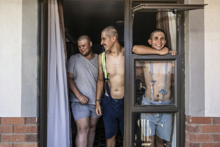 Des étudiants, Belly Sharpe (C), 18, et Eben Mans (D), 20, rient avec un ami à l'entrée de leur dortoir Vaalbos dans l'enclave afrikaner d'Orania en Afrique du Sud, le 28 janvier 2026. ( AFP / CAMILLA RICHETTI )