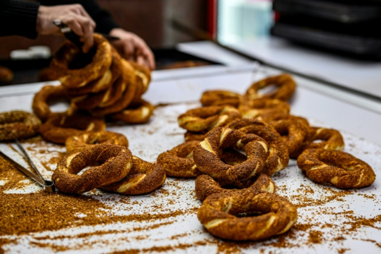 Un vendeur de rue agrémente de sésame ses simits, des petits pains turcs en forme d'anneau, le 27 décembre 2025 à Istanbul ( AFP / Yasin AKGUL )