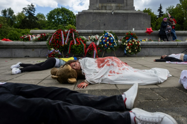 Des manifestants allongés sur le sol, simulent des corps de victimes, pour protester contre l'invasion russe de l'Ukraine, au mausolée des soldats soviétiques à Varsovie, en Pologne, le 9 mai 2025 ( AFP / Wojtek RADWANSKI )