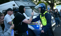 Des manifestants font face à un policier lors d'un rassemblement dans le centre d'Epping, au nord-est de Londres, le 20 juillet 2025 ( AFP / JUSTIN TALLIS )