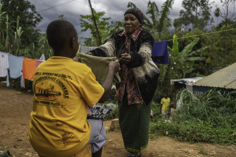 Marie-Thérèse Tsesi, une nourrice de 63 ans, plie du linge avec l'un des cinq enfants orphelins d'Ebola dont elle s'occupe à son domicile à Mongbwalu, dans le nord-est de la RDC, le 11 octobre 2026 ( AFP / MARIE RUWET )