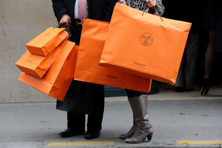 Un couple sort d'un magasin Hermès à Paris avec des sacs à provisions Hermès