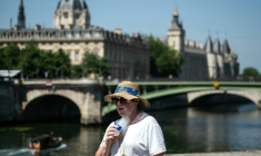 Une femme se rafraîchit avec une bouteille d'eau fraîche dans le centre de Paris, le 21 juin 2026 ( AFP / ARNAUD FINISTRE )