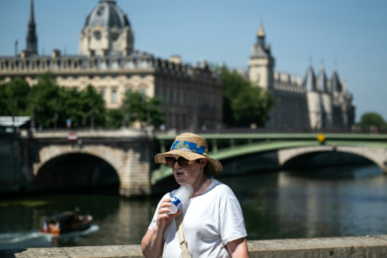 Une femme se rafraîchit avec une bouteille d'eau fraîche dans le centre de Paris, le 21 juin 2026 ( AFP / ARNAUD FINISTRE )