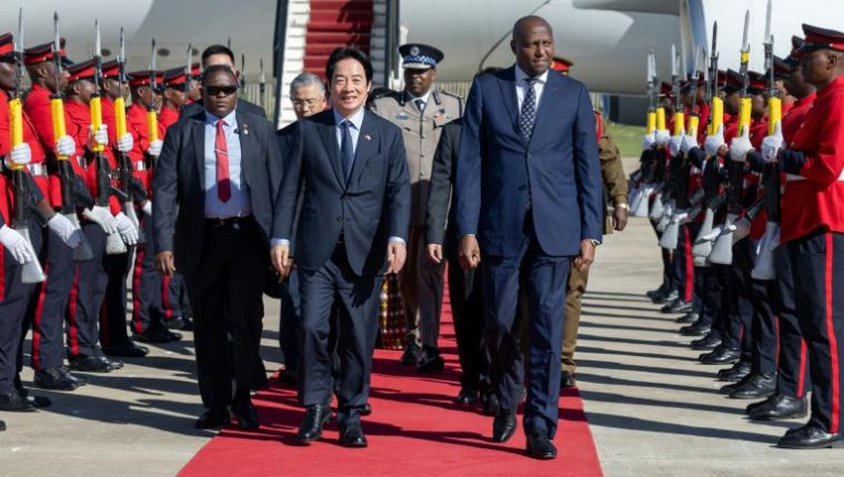 Cette photo de presse, prise et diffusée le 2 mai 2026 par le Bureau présidentiel de Taïwan, montre le président taïwanais Lai Ching-te (au centre) accueilli par le Premier ministre d'Eswatini, Russell Mmiso Dlamini (au centre-droite), à son arrivée à Eswatini, à l'aéroport international King Mswati III de Sikhuphe. Le président taïwanais Lai Ching-te a annoncé le 2 mai 2026 son arrivée en Eswatini, seul allié diplomatique de Taipei en Afrique, après l'annulation d'un précédent voyage suite au retrait des autorisations de survol par plusieurs pays. ( Taiwan Presidential Office / Handout )