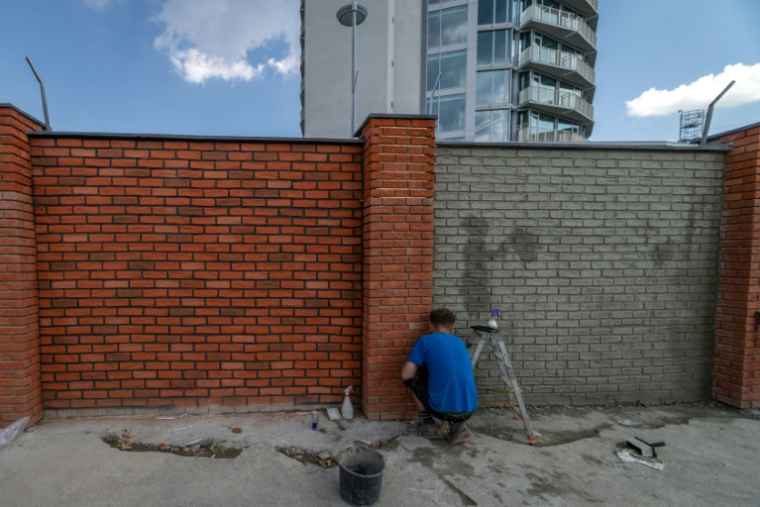 Des ouvriers repeignent le mur d'enceinte du ministère de la Défense slovaque, le 16 juillet 2026 à Bratislava ( AFP / TOMAS BENEDIKOVIC )