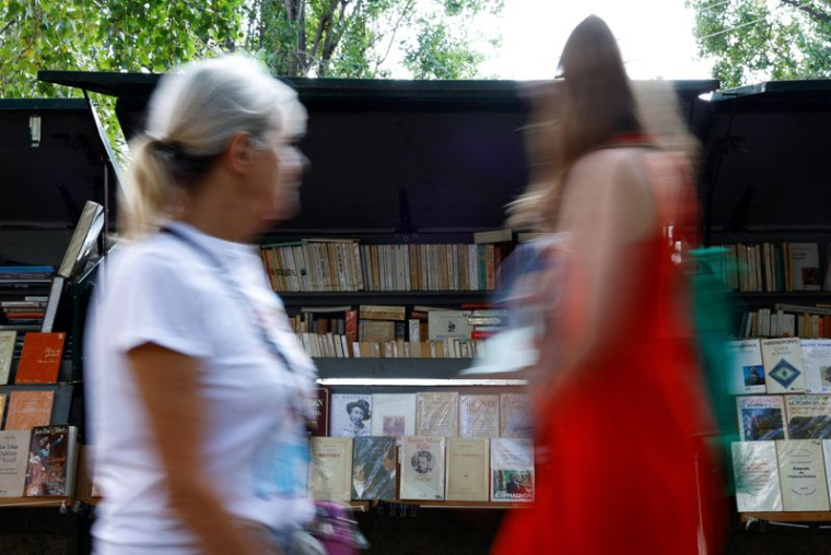 Des personnes passent devant des bouquinistes sur les quais de la Seine à Paris