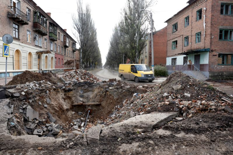 Photo d'archives d'une camionnette passant devant un cratère sur la route après un tir de missile dans la région de Bakhmout
