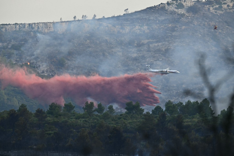 Un Bombardier Dash 8-Q400 de la Sécurité Civile, dispersant du produit retardant près de Fontjoncouse, le 6 août 2025  ( AFP / LIONEL BONAVENTURE )