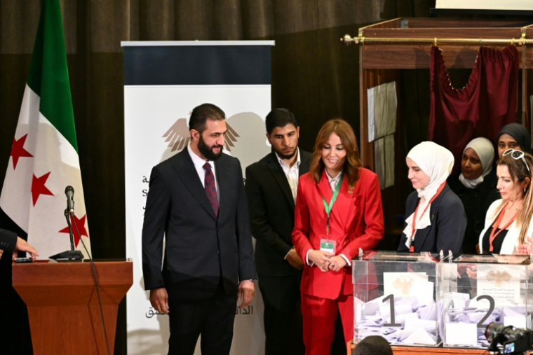 Le président intérimaire Ahmad al-Chareh (g) visite le bureau de vote où les membres des comités locaux syriens votent lors du processus de sélection pour désignerle  premier Parlement de l'ère post-Assad à Damas, le 5 octobre 2025 ( AFP / LOUAI BESHARA )