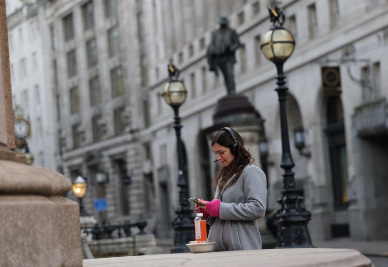 Une employée de bureau prend une pause déjeuner devant la Banque d'Angleterre