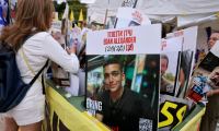 Une femme regarde des portraits d’otages israéliens détenus dans la bande de Gaza, dont un au centre représentant l’otage israélo-américain Edan Alexander, dont la libération est attendue le 12 mai 2025, sur la place des otages à Tel-Aviv, le 12 mai 2025 ( AFP / Menahem KAHANA )
