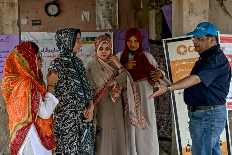 Le nutritionniste Mazhar Iqbal et des travailleuses sociales lors d'un programme de nutrition de l'Unicef au village de Fateh Muhammad Soomro, dans la province du Sindh, le 29 juillet 2025 au Pakistan ( AFP / Rizwan TABASSUM )