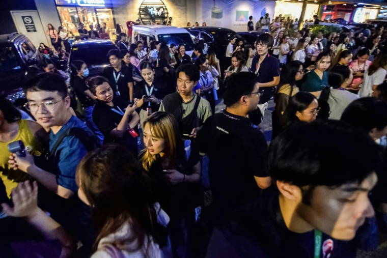Les employés du centre d'appels surfent sur leurs téléphones portables alors qu'ils se rassemblent devant leur immeuble de bureaux après les secousses du tremblement de terre à Cebu, dans le centre des Philippines, le 30 septembre 2025 ( AFP / Alan TANGCAWAN )