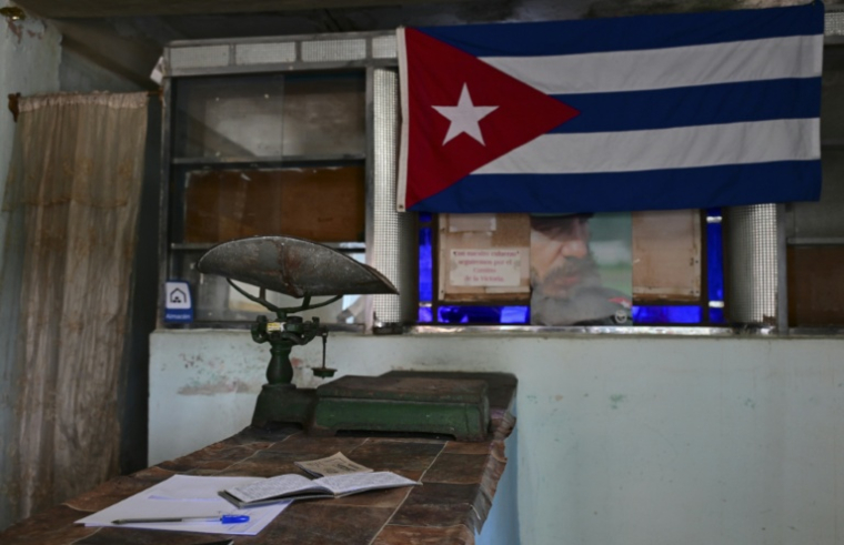 Une vieille balance sur le comptoir d'une épicerie à prix subventionnés, près d'un drapeau cubain et d'un portrait de Fidel Castro (1959-2006), le 5 octobre 2026 à La Havane, à Cuba ( AFP / YAMIL LAGE )