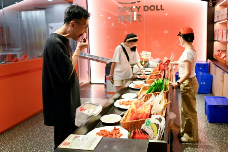 Des clients goûtent des lamelles épicées dans une boutique à Changsha, dans la province du Hunan, le 17 juin 2026 dans le centre de la Chine ( AFP / WANG Zhao )