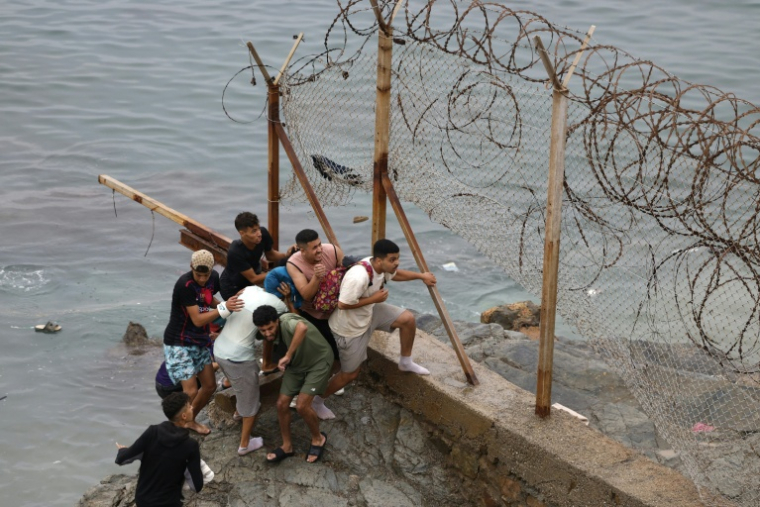 Des hommes se rassemblent le long d'une clôture près de la ville marocaine de Fnideq, située à la frontière avec l'enclave espagnole Ceuta, le 31 juillet 2026 ( AFP / Abdel Majid BZIOUAT )