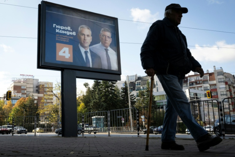 Une personne marche devant une affiche électorale du candidat à la présidentielle bulgare Andrey Gyurov et de son partenaire pour la vice-présidence Georgi Kandev, à Sofia, le 23 octobre 2026 ( AFP / Nikolay DOYCHINOV )