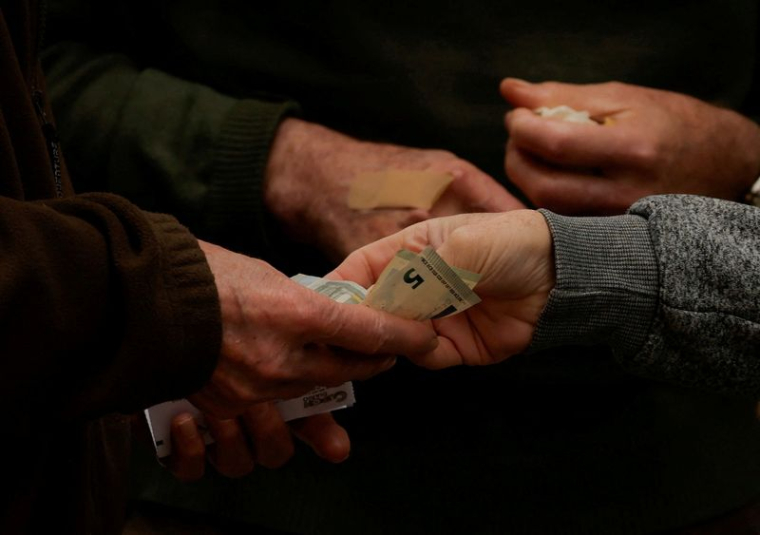 Un client paie un vendeur de loterie de rue avec des billets de cinq euros