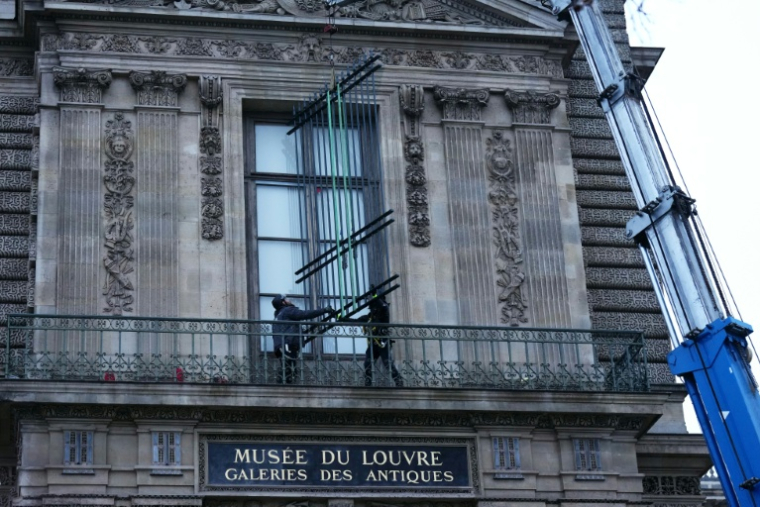 Des ouvriers installent une grille de protection devant la fenêtre de la galerie d'Apollon du  musée du Louvre, le 23 décembre 2025 à Paris ( AFP / Dimitar DILKOFF )