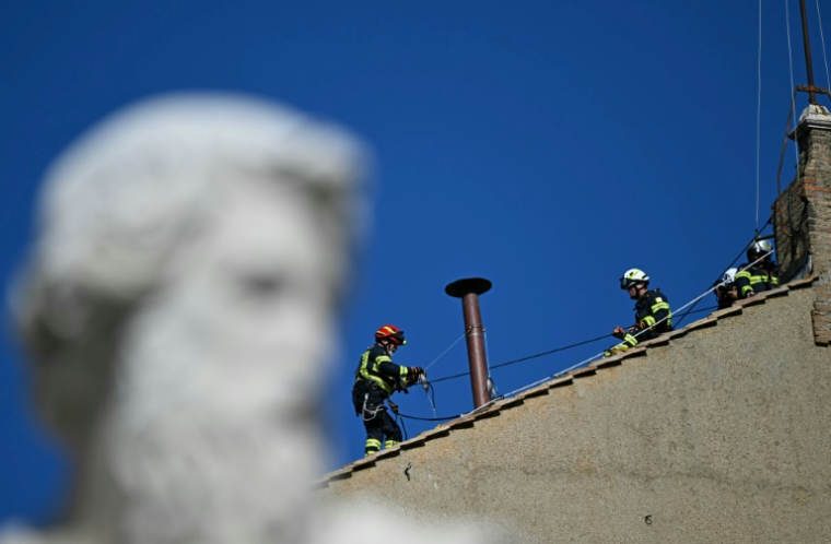 Des pompiers installent une cheminée sur le toit de la Chapelle Sixtine, au Vatican, quelques jours avant le début du conclave, le 2 mai 2025 ( AFP / Gabriel BOUYS )