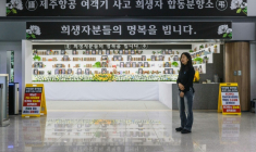 Lee Hyo-eun devant un autel commémoratif dédié aux victimes du crash du vol 2216 de Jeju Air en décembre 2024, dans le hall des arrivées de l'aéroport international de Muan, le 14 décembre 2025 en Corée du Sud ( AFP / ANTHONY WALLACE )